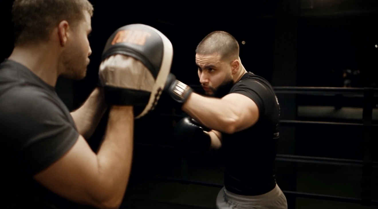 Zack Lalouti practicing kickboxing with a trainer holding pads.