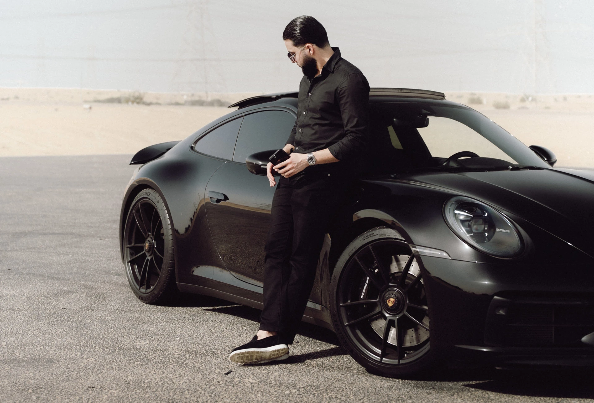 Zack Lalouti leaning against a black Porsche in Dubai.