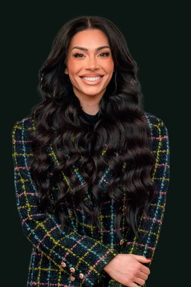 Leila Hormozi smiling, wearing a dark patterned blazer over a black outfit.