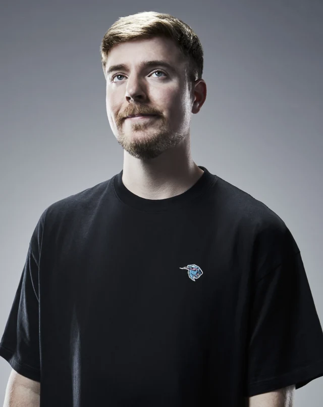 Studio portrait of MrBeast wearing a black T-shirt against a grey background.