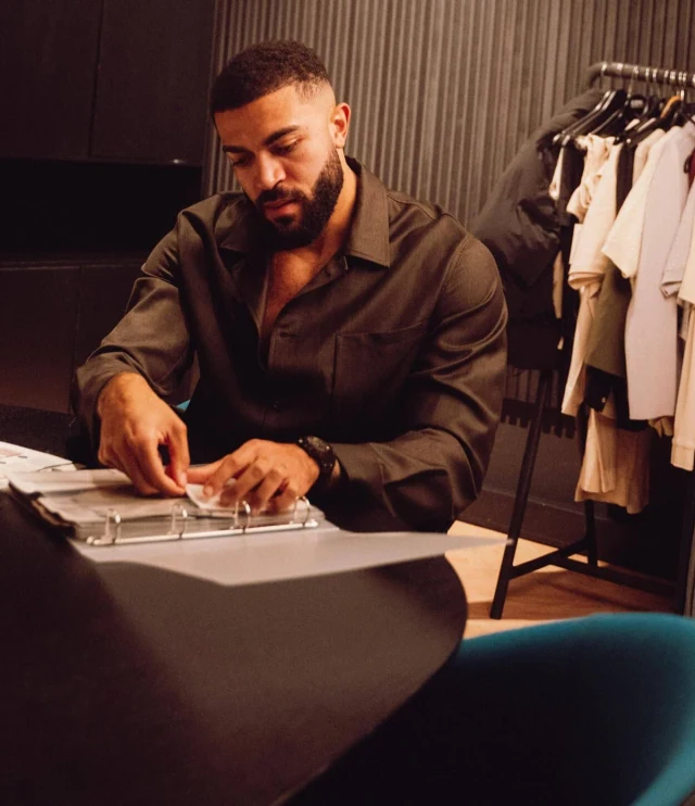 Samuel Onuha wearing a brown collared shirt while working at a desk in the ICON Amsterdam showroom.