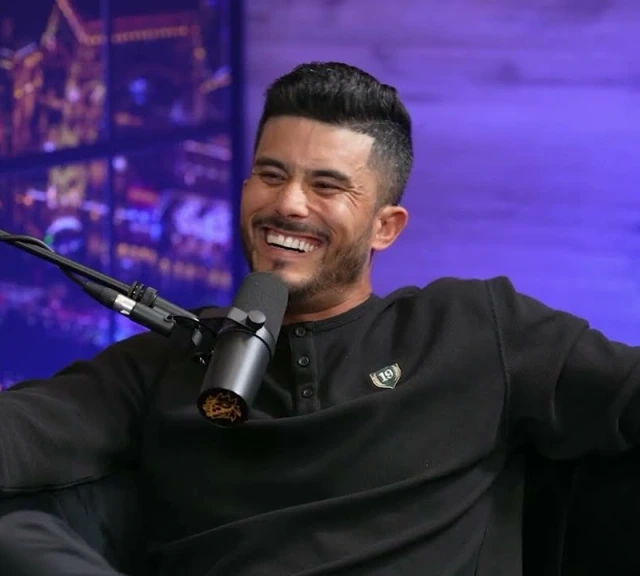 Ryan Pineda smiling in a dark sweatshirt in his podcast studio.